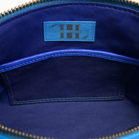 Close-up of a blue leather bag with a brand label on a dark blue background