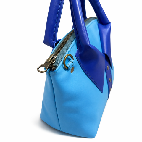 Close-up of royal blue collar and brass zipper on sky blue lambskin crossbody handbag