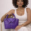 Handmade royal purple lambskin leather bag with collar detail and rolled top handle, held by model — Inspired Leather Co.