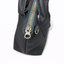 Close-up of YKK antique brass zipper pull and D-ring hardware on handmade black pebbled cowhide collar bag
