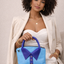 Woman holding a sky blue handbag with a royal blue collar design against a neutral background