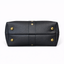 Bottom view of black pebbled leather collar bag showing four antique brass protective purse feet and center leather detail
