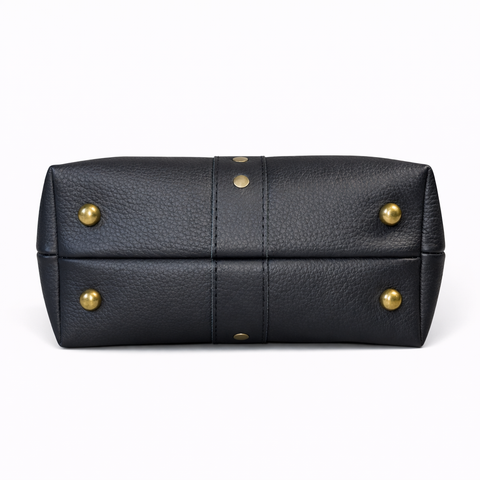 Bottom view of black pebbled leather collar bag showing four antique brass protective purse feet and center leather detail