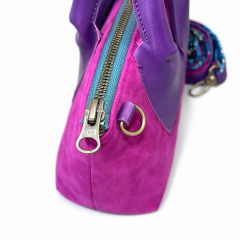 Close-up of YKK antique brass zipper pull and D-ring hardware on handmade magenta suede collar bag