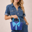 Woman holding a blue handbag with a matching denim design against a beige background