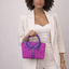Handmade magenta suede and purple lambskin collar bag with rolled top handle, held by model — Inspired Leather Co.