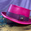 Pink Leather Pork Pie Hat with a purple hat band  with a jewel against a purple backdrop